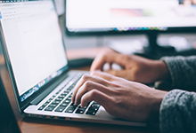 hands typing on laptop at an office desk