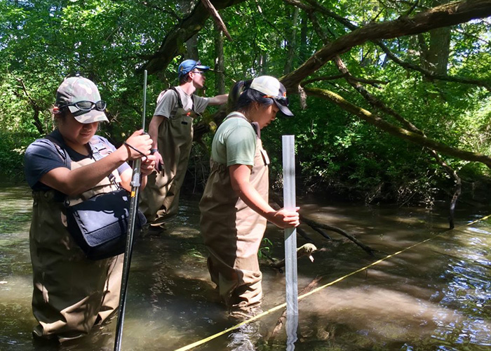 Eli Escobar (from left), a student in the Women In Natural Sciences program, volunteer Matt Tursi, and Academy field team leader Amanda Chan measure the depth and flow rate of the water and the vegetation as part of a fish survey at Cherry Creek near Stroudsburg. Photo by Allison Stoklosa