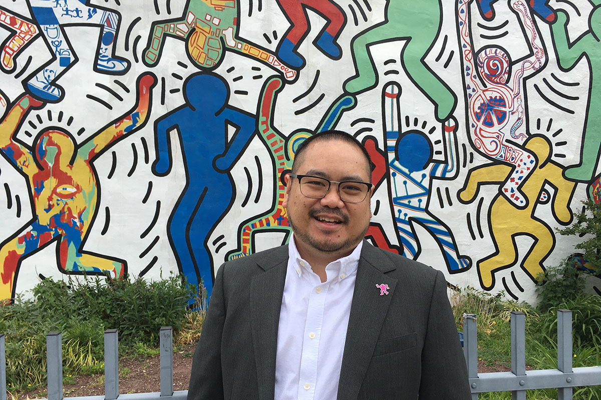Nic John Ramos stands in front of a Keith Haring mural