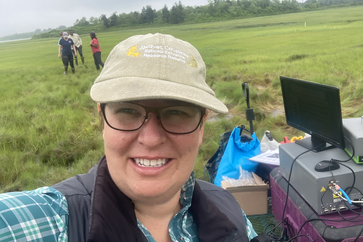 Elizabeth Burke Watson in the foreground with students standing in the background at Narragansett Bay National Estuarine Research Reserve