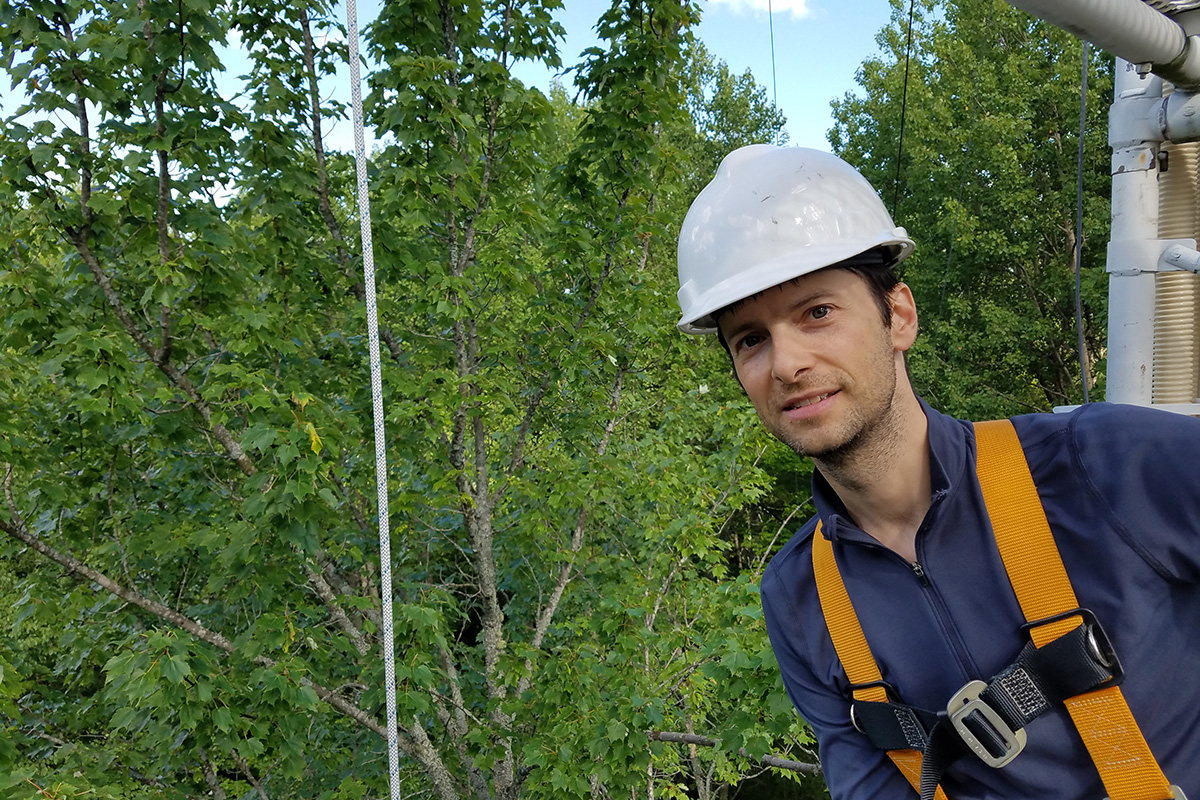 Ezra Wood in hard hat midway up a sampling tower with trees in background