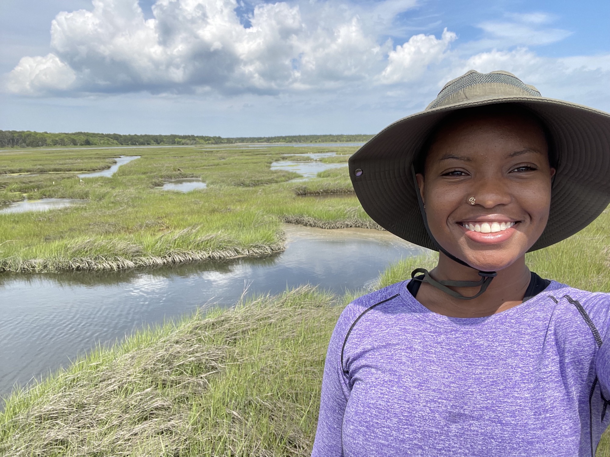 Akilah Chatman smiles outside in front of wetlands
