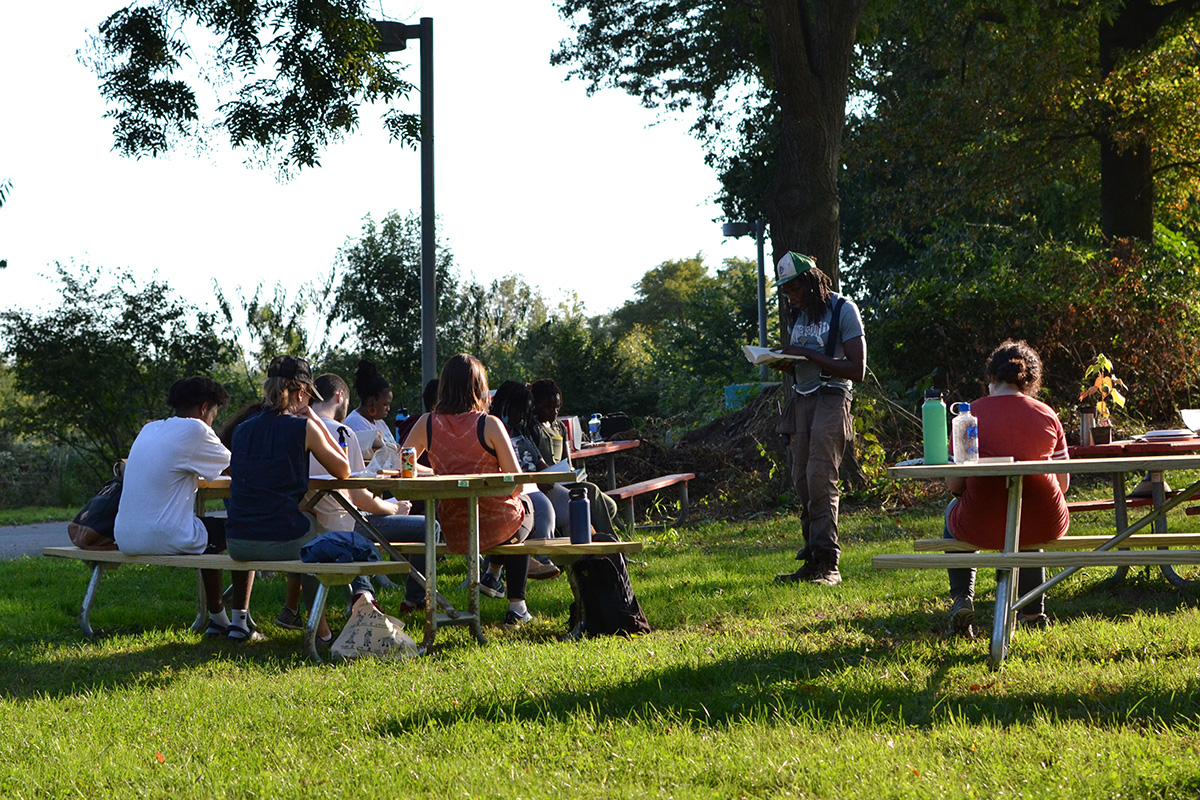 Chris Bolden-Newsome and Lessons of Da Land participants gather in the picnic area and read passages from The Cooking Gene by Michael Twitty