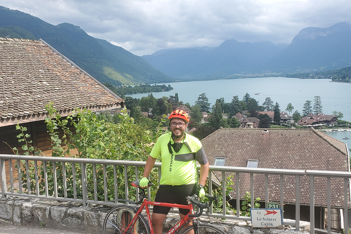Alejandro Manga stands with his bike in front of Annecy Lake in the French Alps