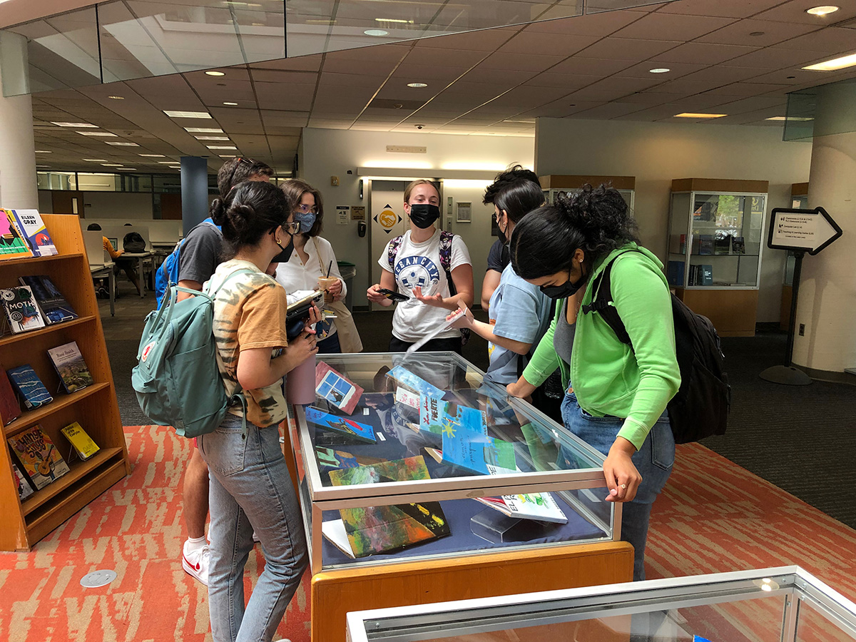 Students in Hagerty Library stand around the Drexel Cartonera exhibition of handmade cardboard books