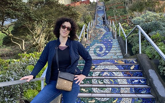 poet daisy fried stands on a staircase that is decorated with a spiral tile mosaic