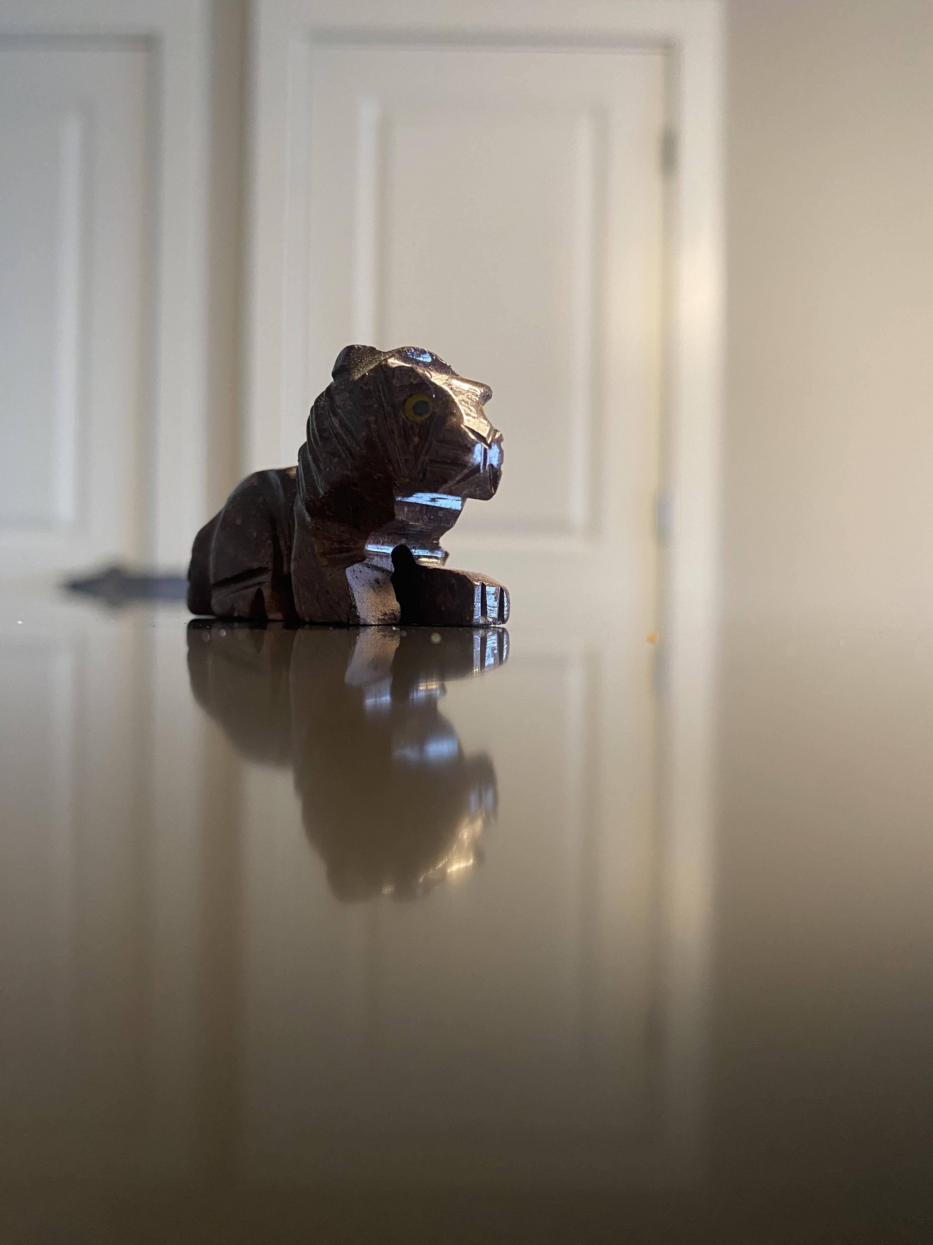 close up of a small figure of a lion sitting on a reflective floor