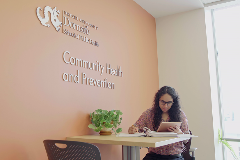 Claudia Zumaeta Castillo, MPH ‘20 , sits at a desk in the Community Health and Prevention department lobby