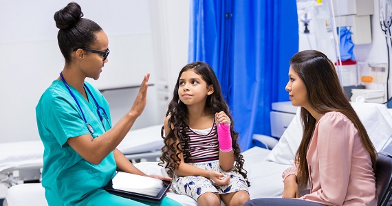 Child in the emergency room with mother speaking with medical professional