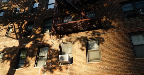 Tree casts a shadow on exterior wall of an apartment building