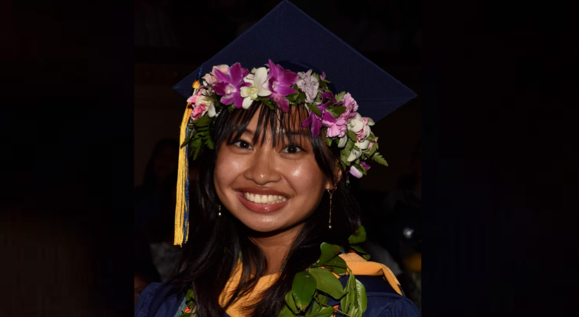 Student at commencement 2024 in her cap and gown smiling