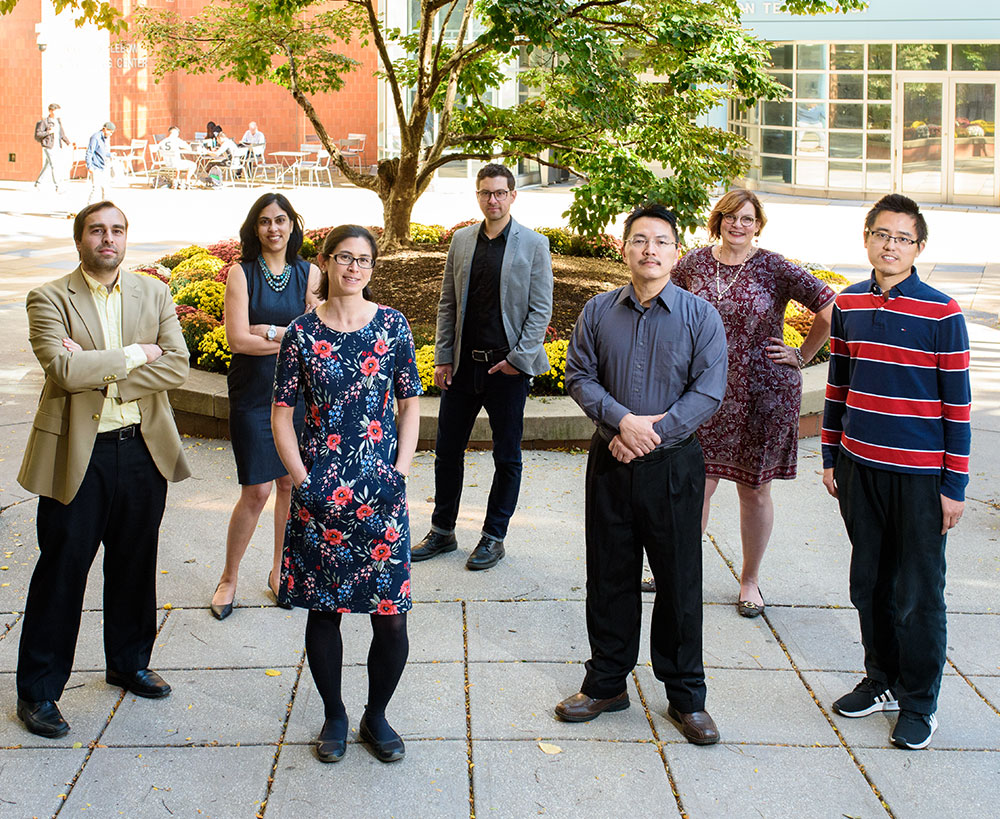 Six faculty members standing in the courtyard