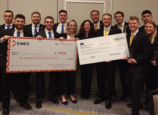 A group of students posing with giant checks for competition awards