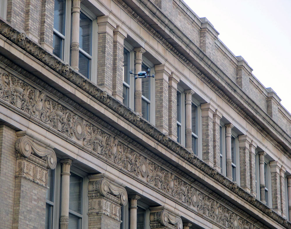 A drone surveys the exterior of Main Building.