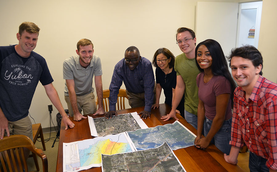A group of students and faculty members looking at maps on a conference table