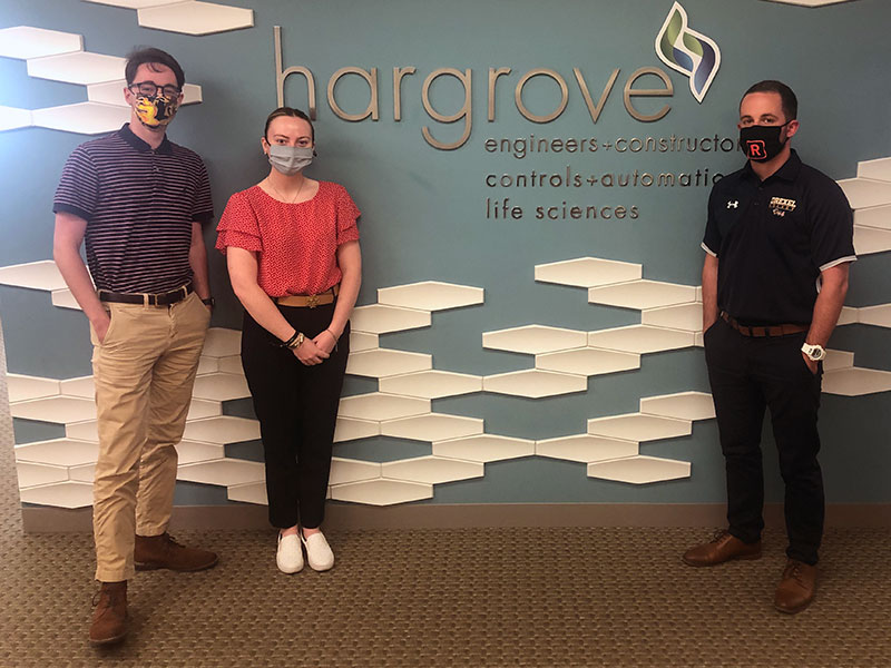 Three students in front of a sign that says Hargrove Engineers