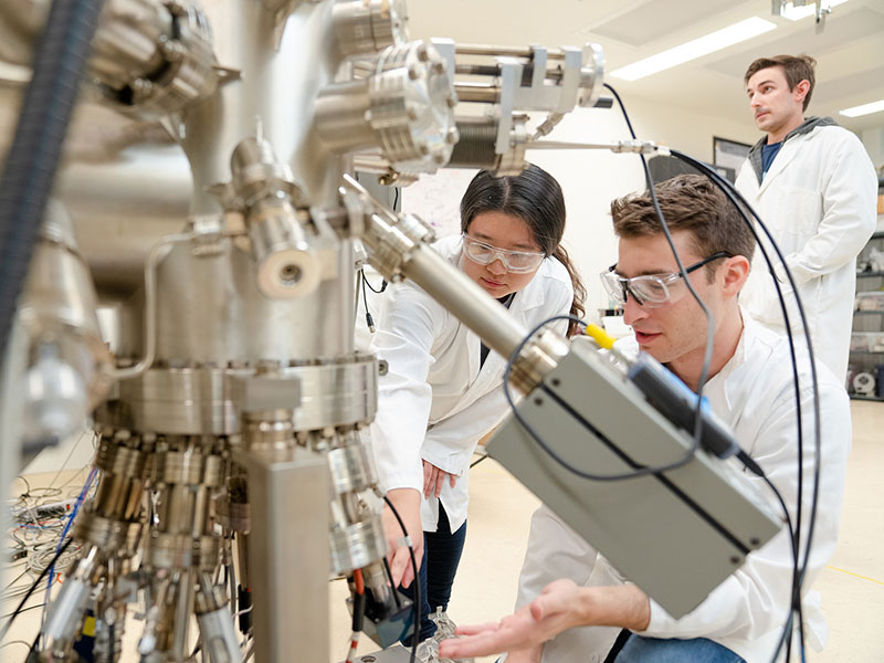 Students in lab coats working on engineering equipment