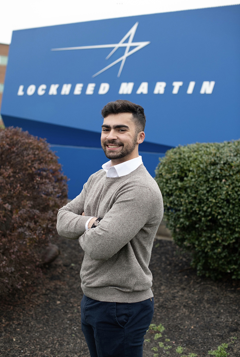 Santiago Sosa stands in front of a Lockheed Martin sign.