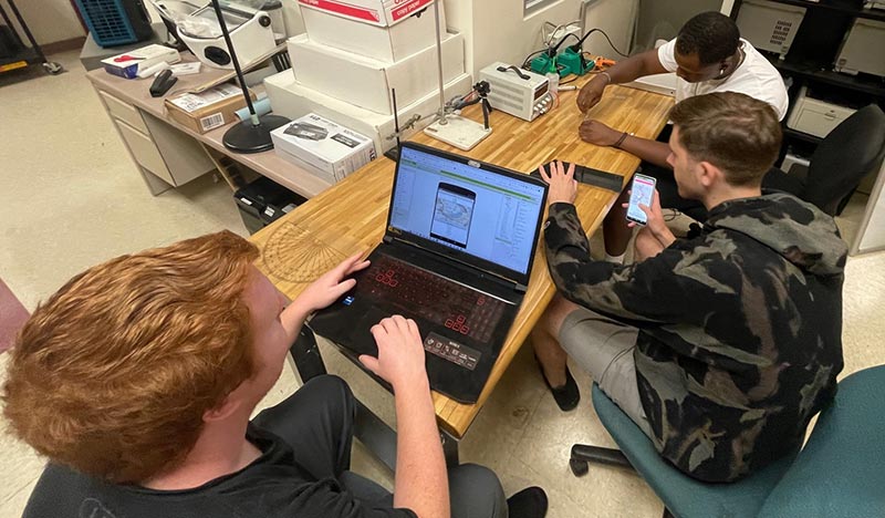 Drexel Students working at a laptop and on a device.
