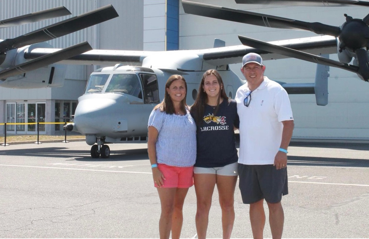 Maddie White and her parents stand in front of a military helicopter.