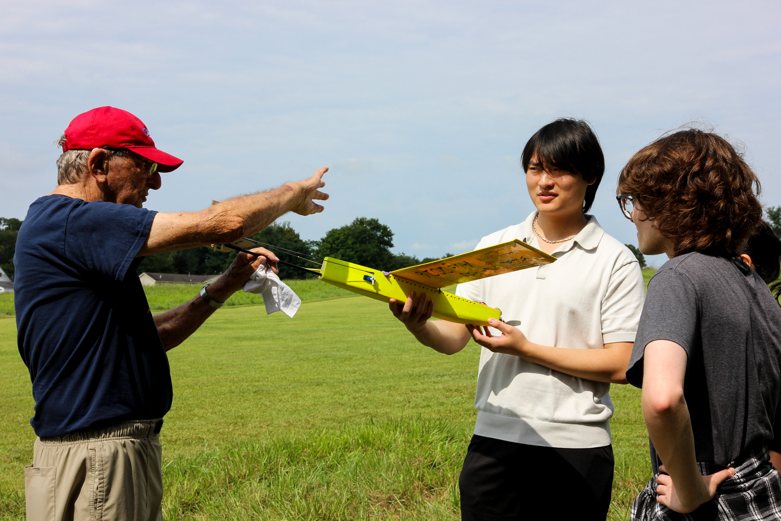 Students review a model airplane with a member of the Propstoppers RC Club.