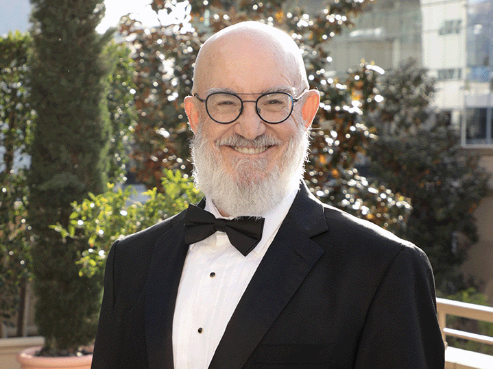 Howley, a man with a white beard, poses in a tuxedo.