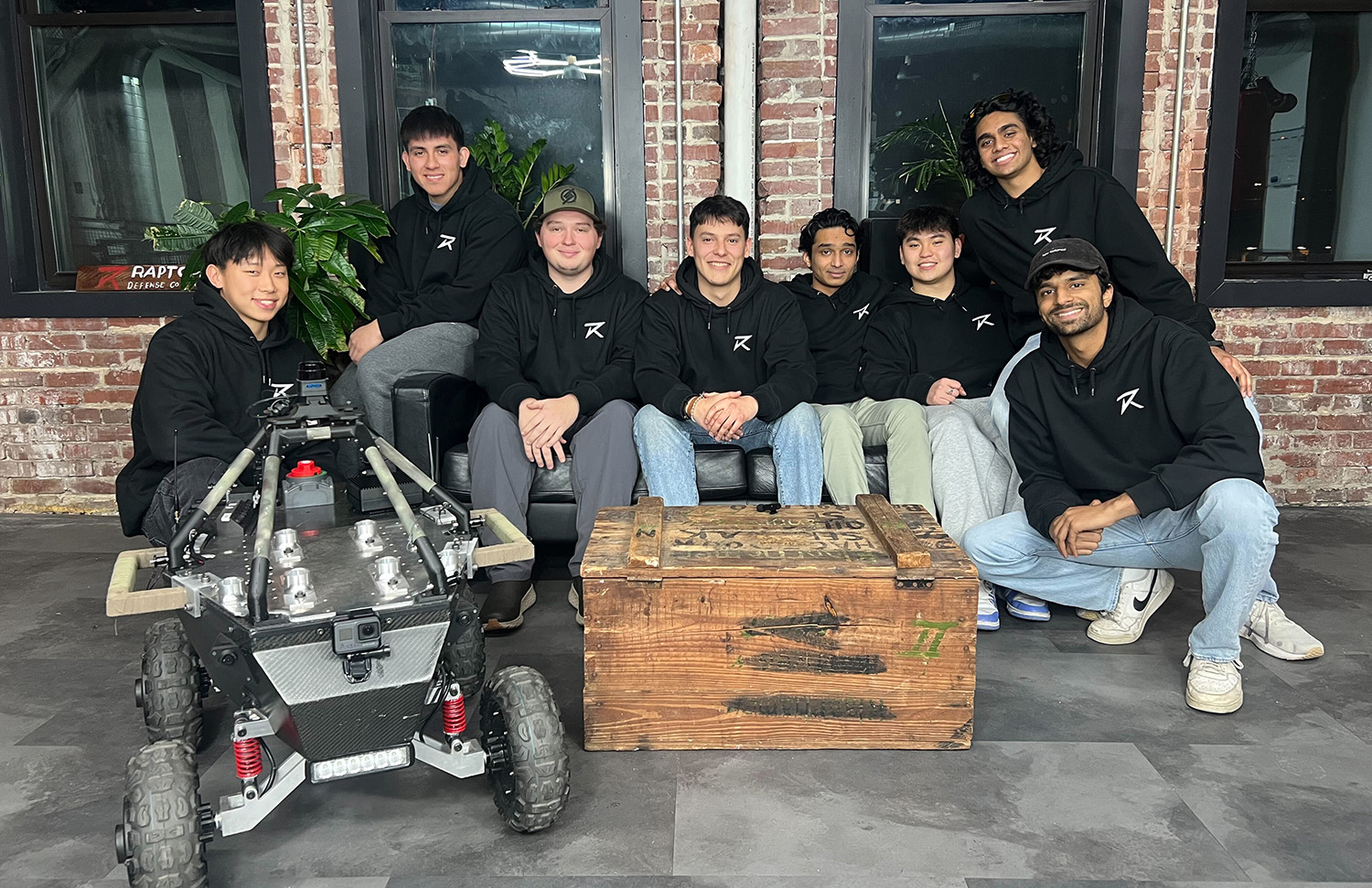 A team of students stands with a rover.