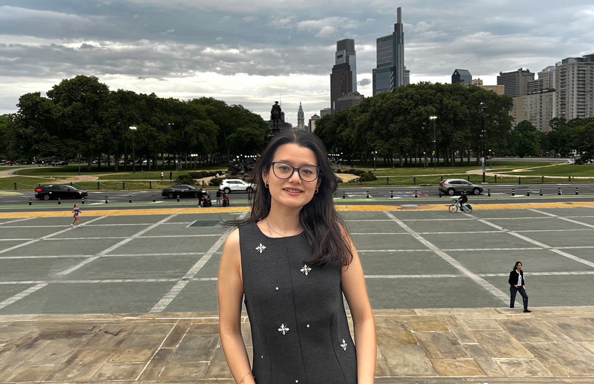 Pradhan stands on the steps of the Philadelphia Art Museum, with the skyline behind her
