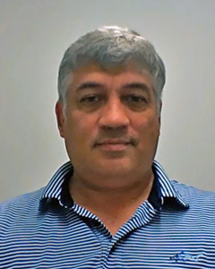 Headshot of Miguel Pando in front of grey background wearing blue striped shirt.