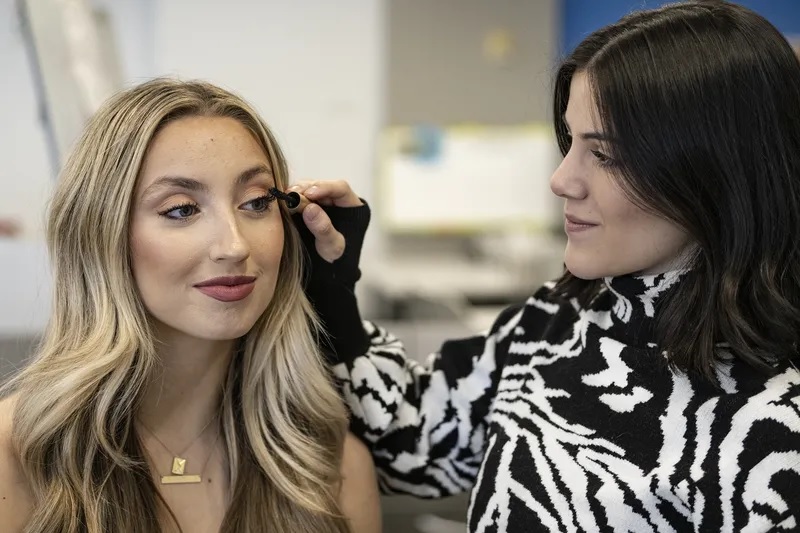 Paige DeAngelo applies mascara to client