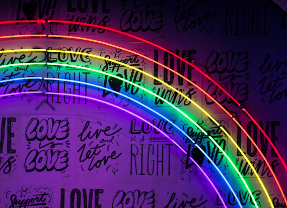 Colorful rainbow lights are displayed in front of a wall with Love written on it.