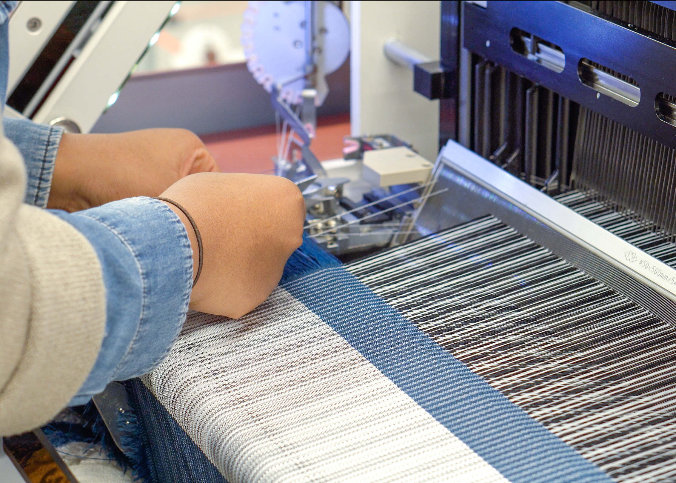 A person operating an automatic weaving loom