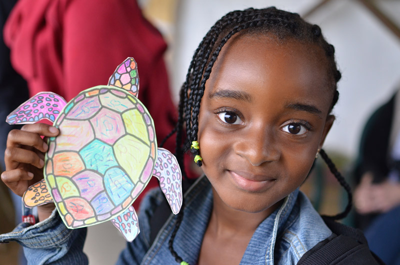Young girl holds a sea turtle made of colored paper