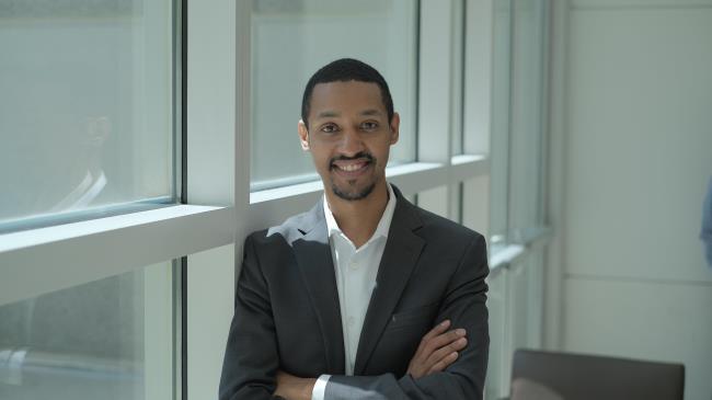 Young man in business suit smiling with arms crossed