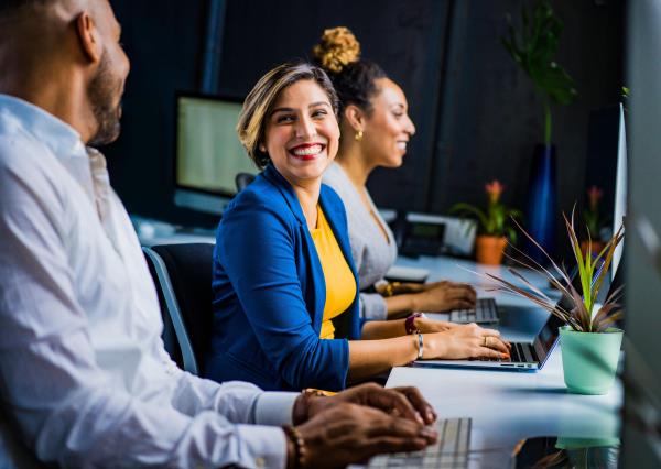 woman smiling at a computer facing a colleague