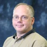 man in brown polo with glasses