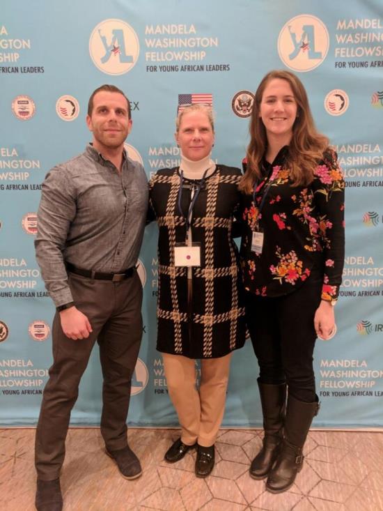 Three educators in front of the Mandela Washington Logo