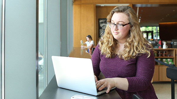an adult learner attends class via laptop from a coffee shop
