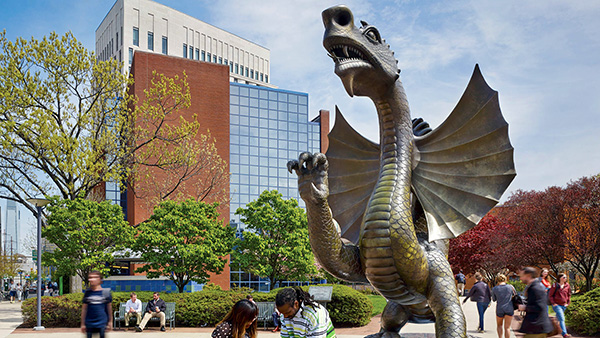 Students gather around a statue of Mario, the Drexel Dragon