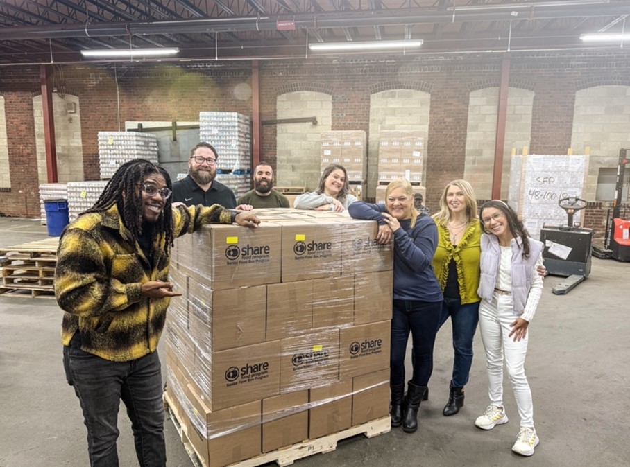 Members of Drexel University's Goodwin College of Professional Studies smile while working at the Share Food Program.