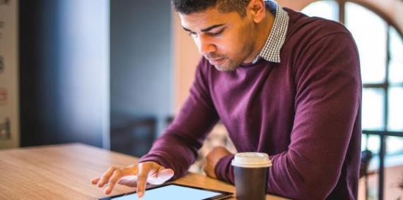 man working at table with a tablet and coffee