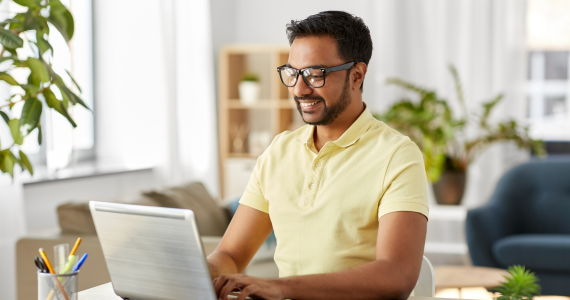 man in glasses seated at desk on laptop