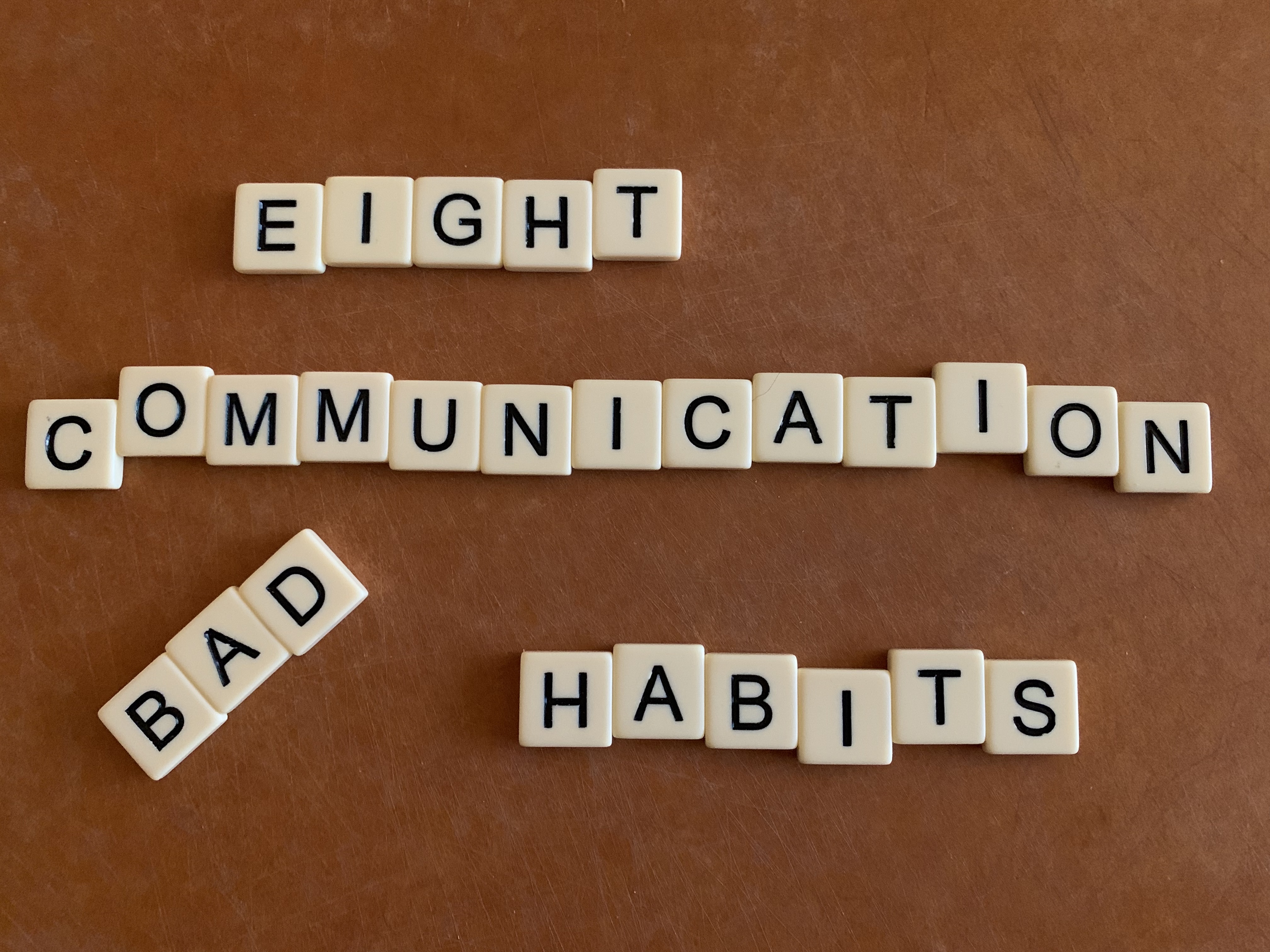 Scrabble-type tiles spelling out the words: eight communication bad habits, with the word bad at an angle