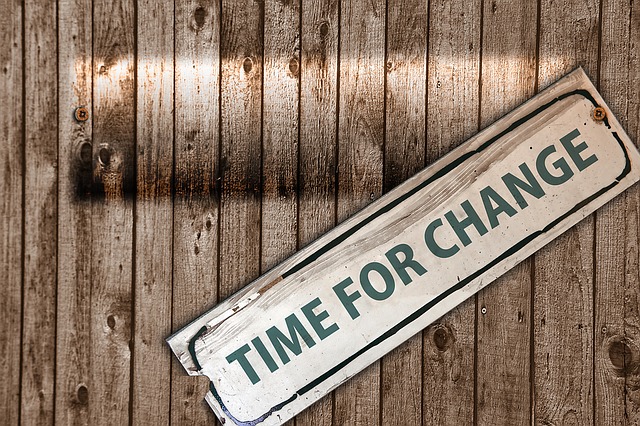 Image of a wooden fence with a dangling sign that reads: Time for Change