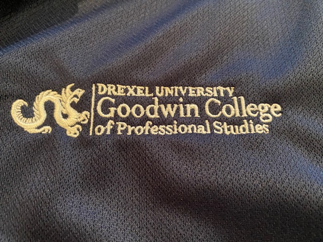 Embroidered logo of Goodwin College in white on a navy fabric