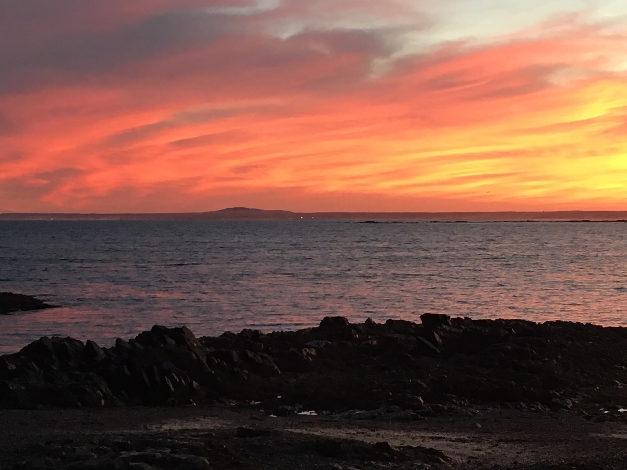 Image of a rocky coastline at sunset with red skys