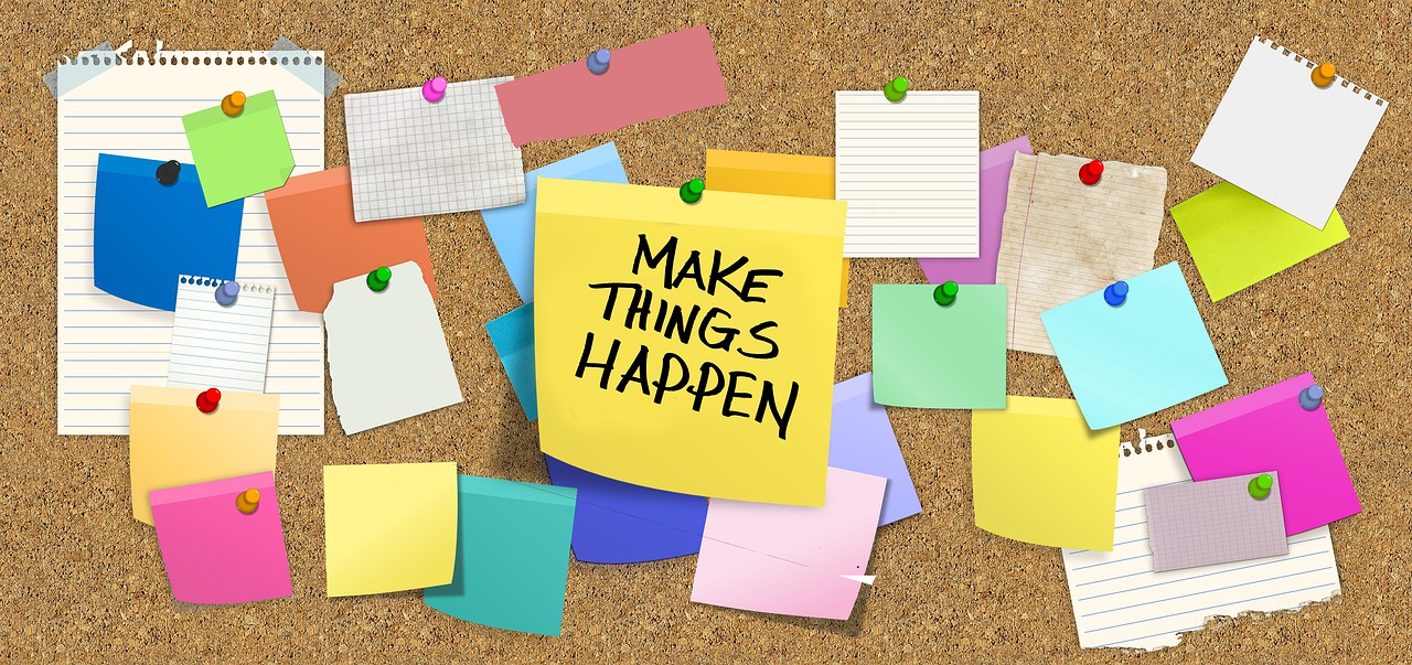 Bulletin board covered in colorful sticky notes, with a large one in the middle that says, "Make Things Happen."