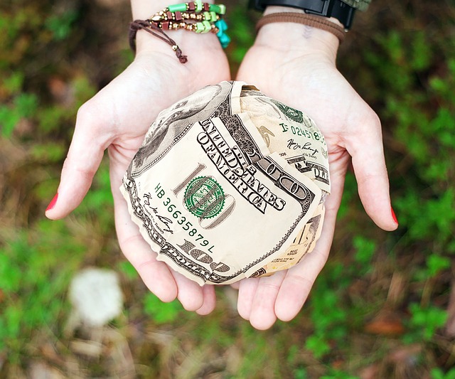 Image of a young person's open hands holding a rolled up ball of money