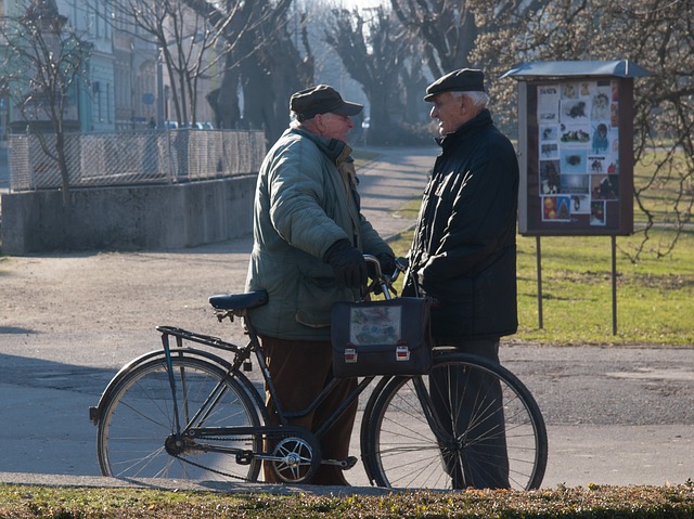 Two neighbors talking as they run into one another. Older men, one with a bicycle