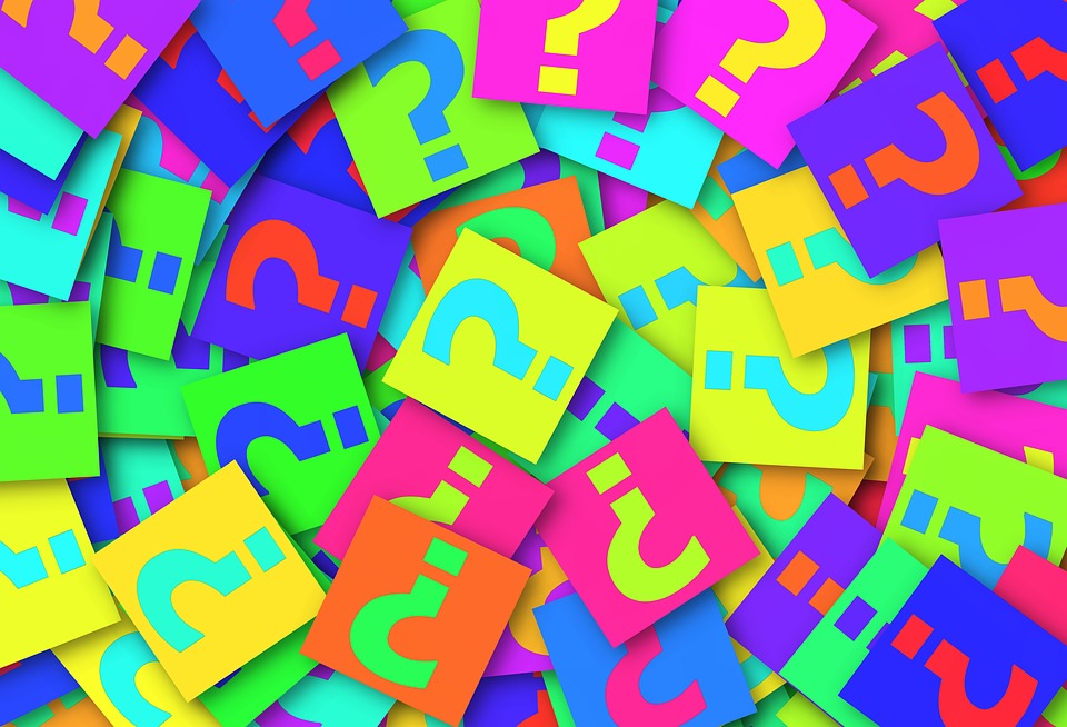 Set of colorful tiles all with a question mark piled up in a fanned-out presentation - as if stacked on top of one another.